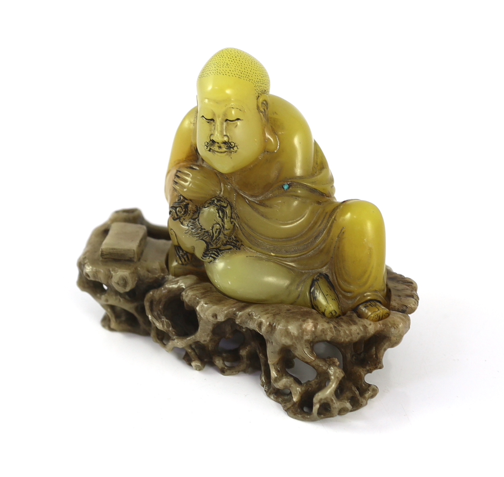 A Chinese soapstone seated group of a luohan and a lion-dog, on a soapstone stand, 18th century